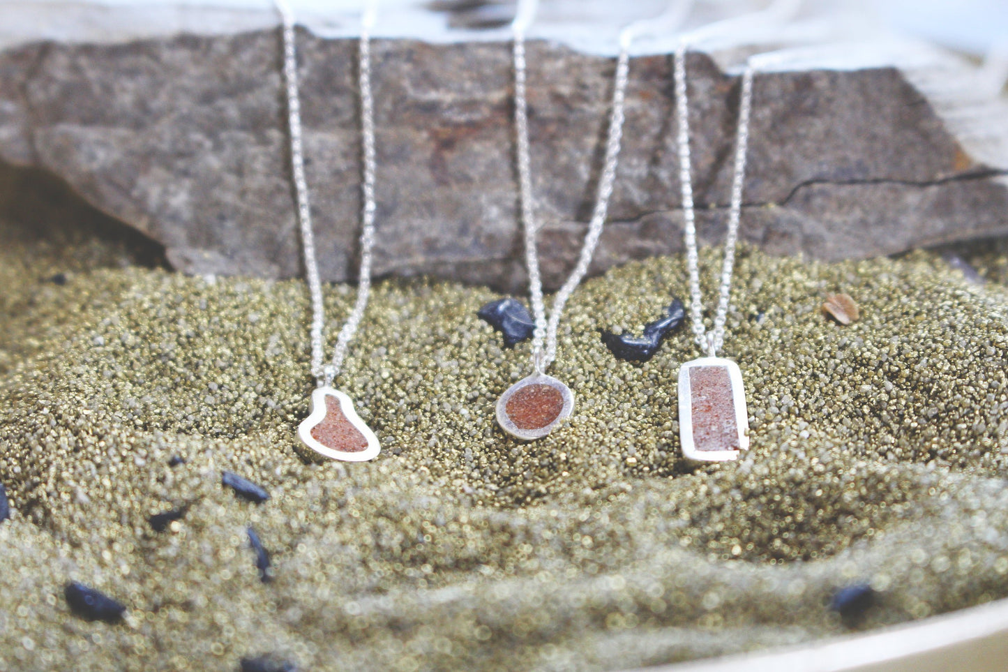 three silver pendants with desert sand inlay