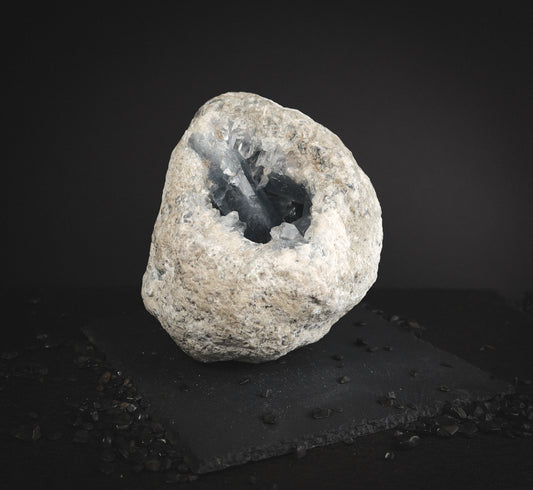 a big raw Celestine geode rounded shape with a hole in the middle showing an inside of the blue crystal