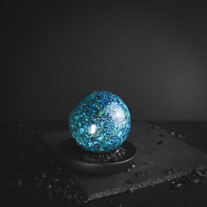 Multicoloured Chrysocolla sphere on a black pedestal.