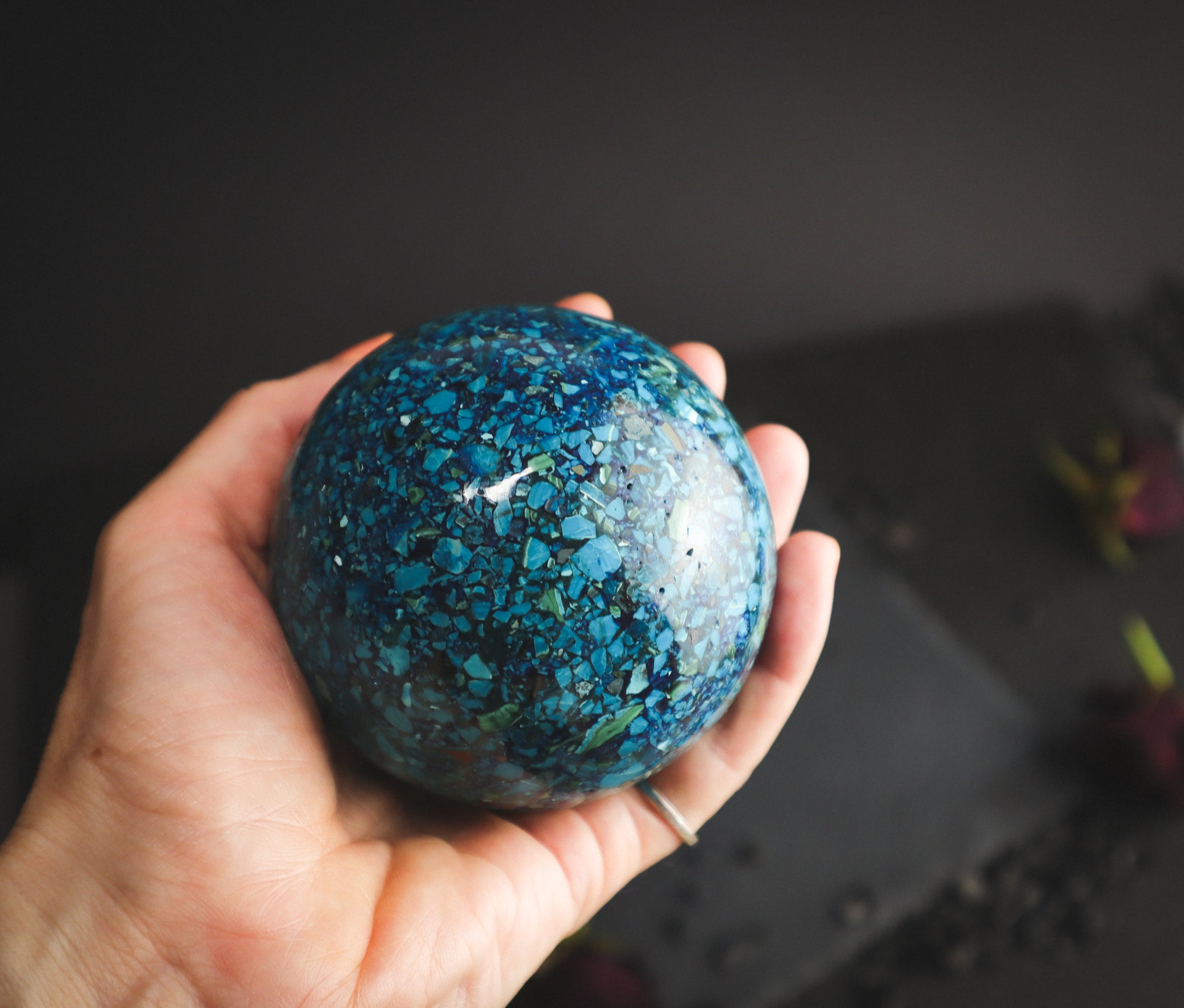 Chrysocolla sphere in a hand for comparison.