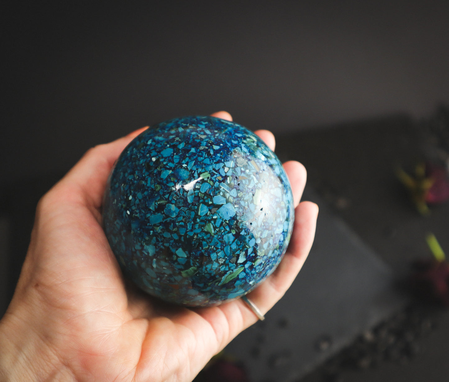 Chrysocolla sphere in a hand for comparison.