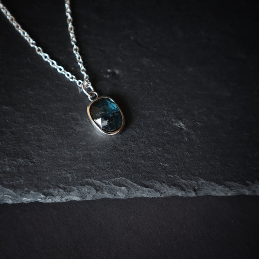Artisanal silver pendant with a deep blue crystal.