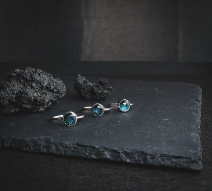 A trio of artisanal silver rings with crystals of different shades of blue.