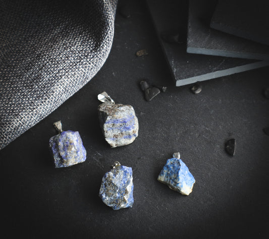 Raw lapis lazuli pendants on a dark background.