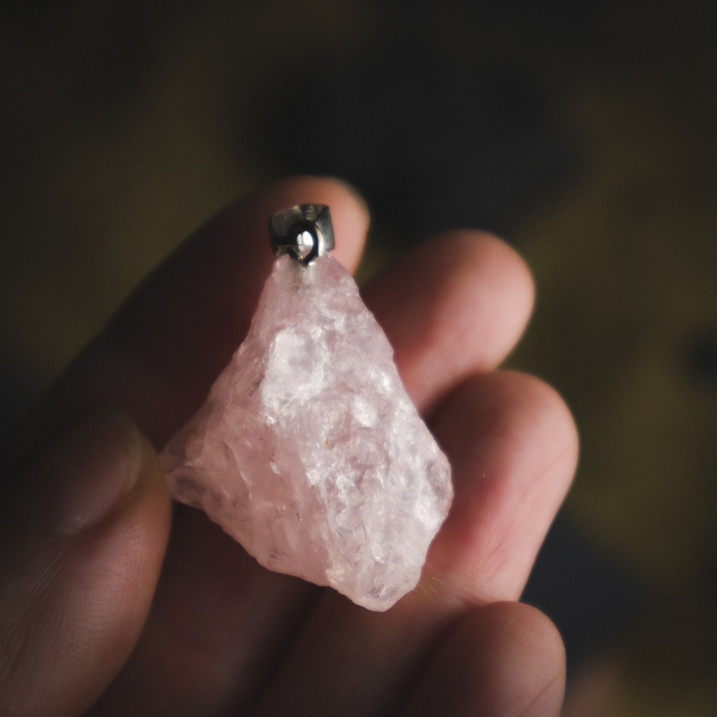 Pink-coloured pendant in a hand for comparison. je na ROŽEVEC (Surovi) - Obesek  je kamen čiste brezpogojne ljubezni.