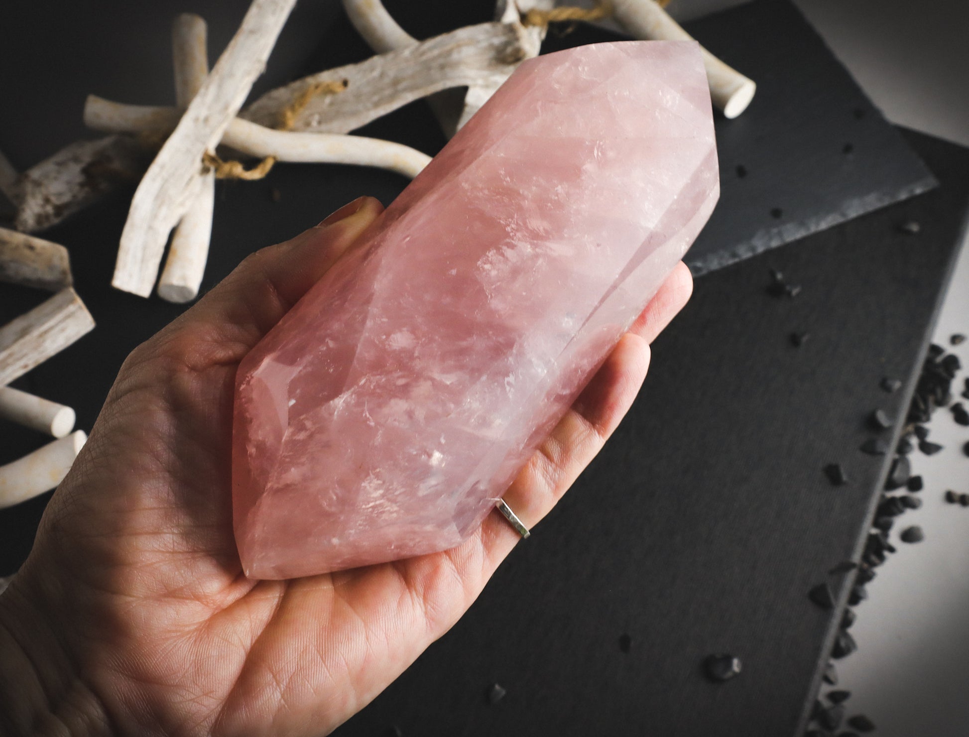 Double-pointed rose quartz in a hand for comparison.