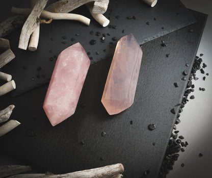 Double-pointed rose quartz crystals on a dark plate.