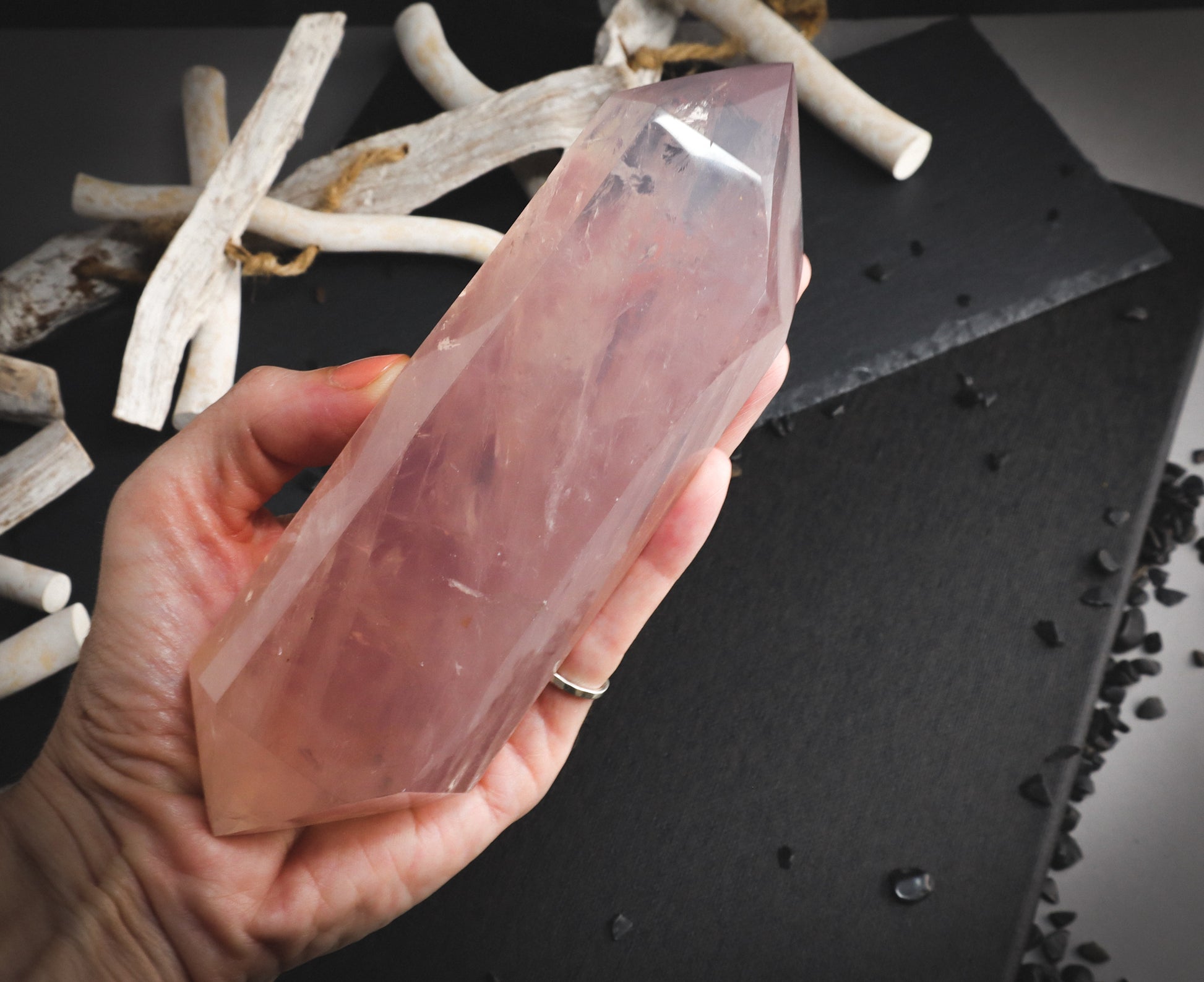 Double-terminated transparent rose quartz stones in a hand.