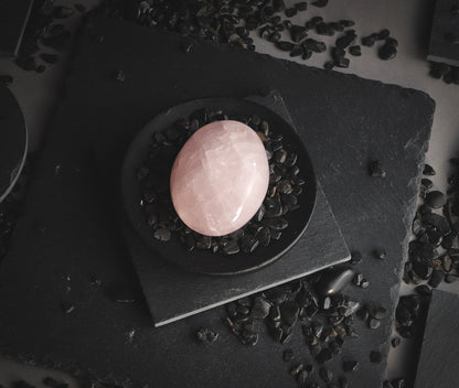 Polished pink stone on a black sand.