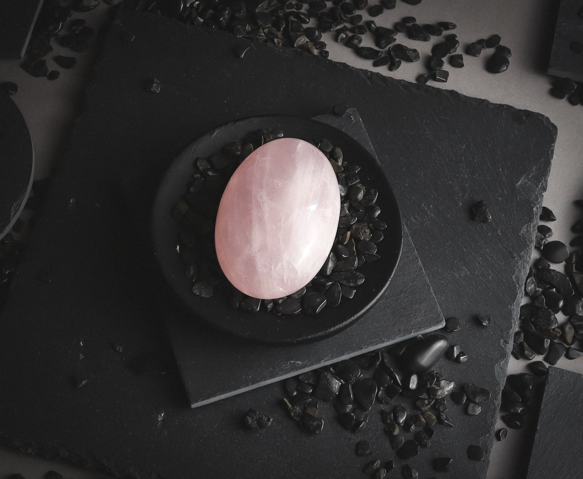 Polished rose quartz palmstone on a black plate.