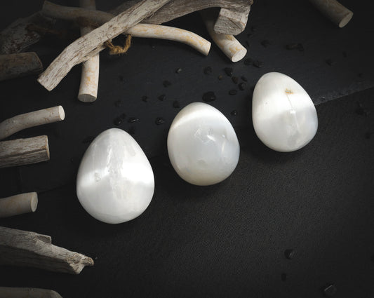 Polished selenite eggs on a dark background.