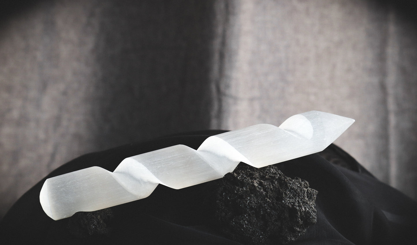 Spiral selenite wand on a dark table.