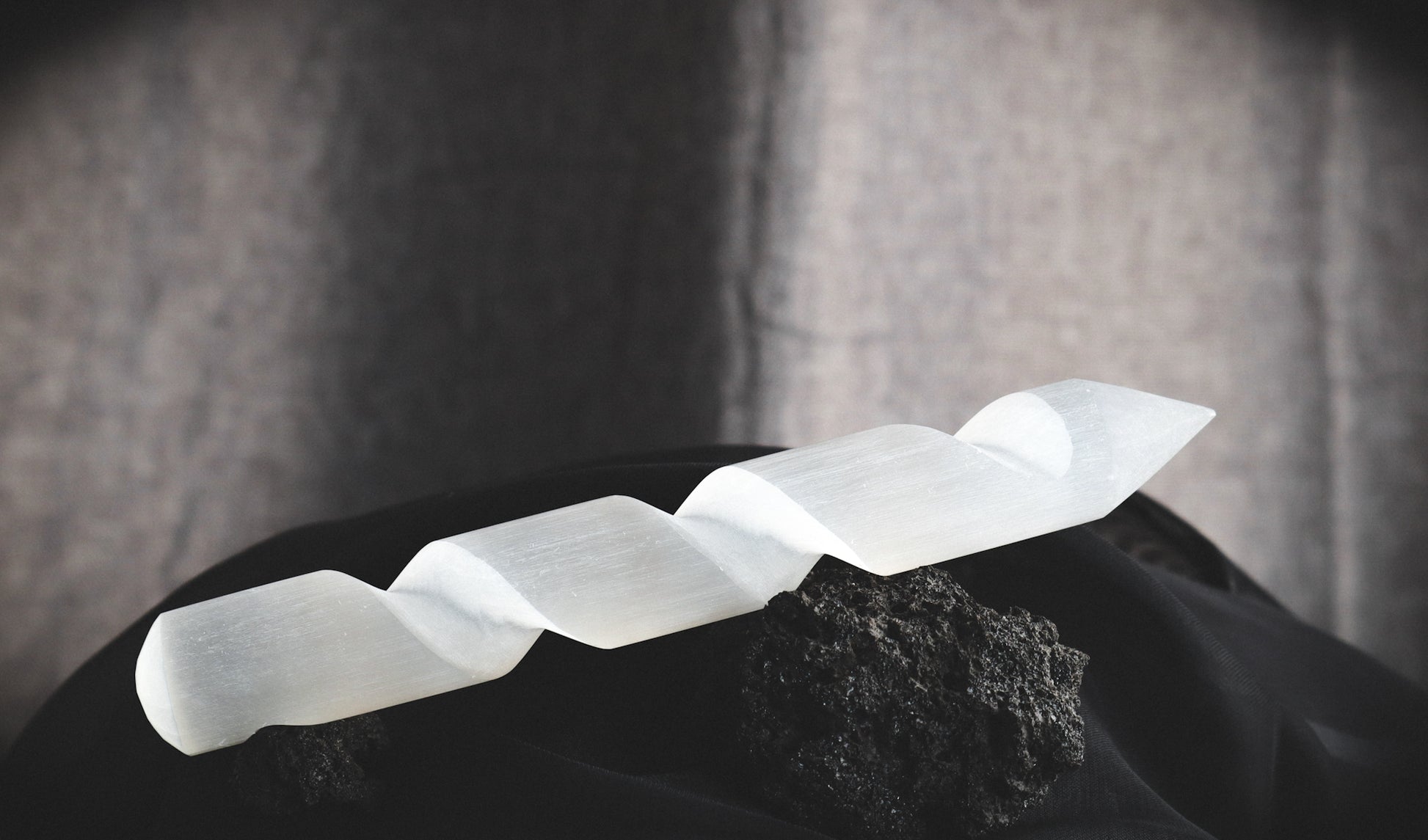 Spiral selenite wand on a dark table.