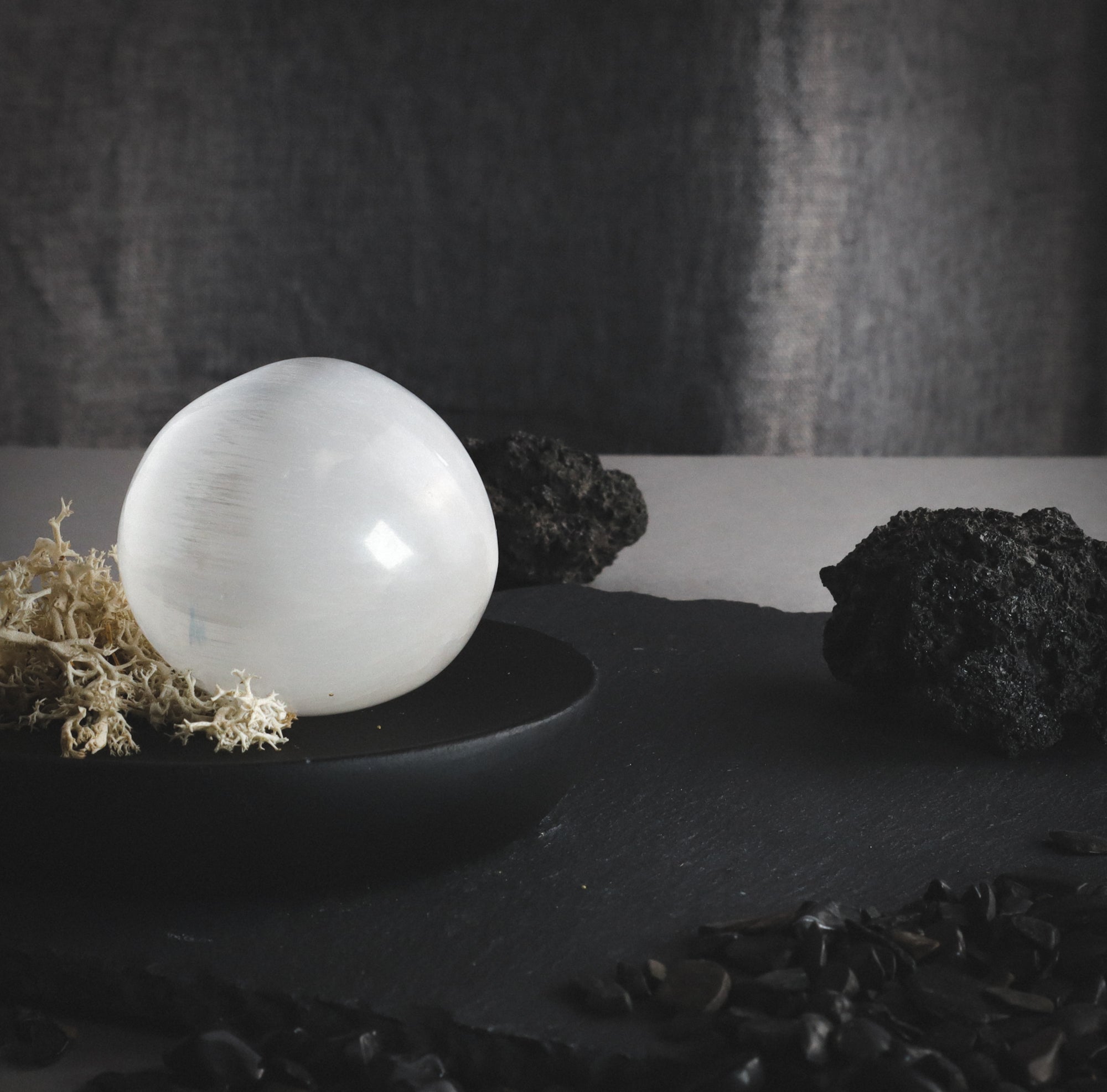 Selenite sphere with vulcanic rocks on a table.