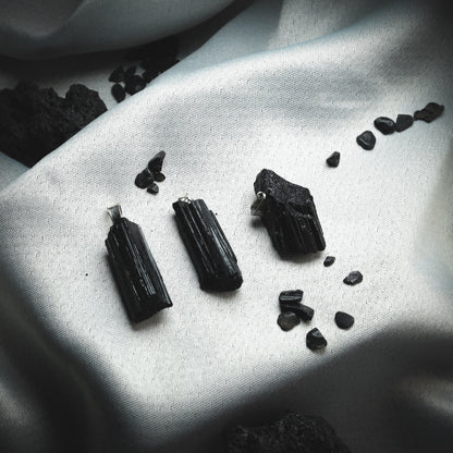 Black tourmaline pendants against a silver background.